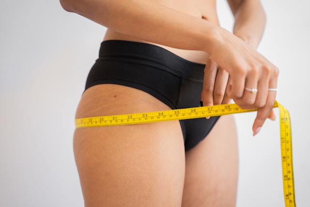 woman measuring hips with yellow measuring tape