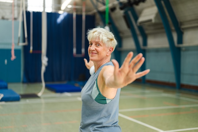 senior woman stretching arms in gym