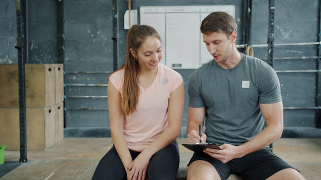 Mission Viejo fitness coach sitting with client reviewing workout plan